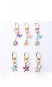 Detail of metal butterfly and starfish keychains with colorful enamel and faux pearls