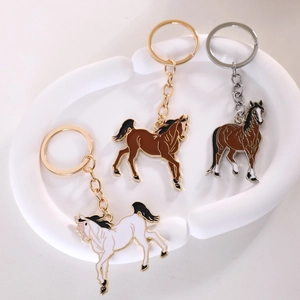 Three horse metal keychains in gold and silver finishes on a white decorative plate