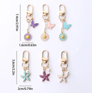 Golden keychain featuring butterfly, daisy, and starfish charms with elegant faux pearls