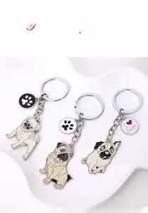 Détails de trois porte-clés Carlin en émail avec breloques I Heart Dogs sur plateau blanc
