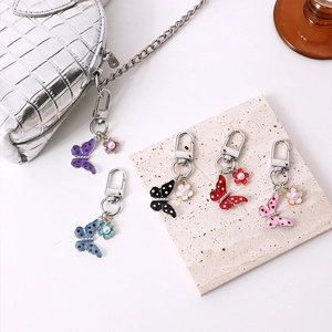 Five butterfly alloy keychains with colorful enamel wings and pearl flower accents on a bag