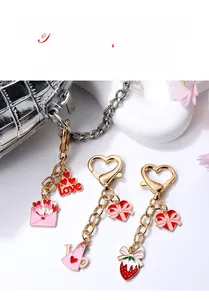 Detail of heart-shaped metal keychains with pink enamel strawberry and love pendants