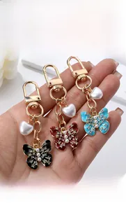 Détails des porte-clés papillon avec émail, perles et attaches en métal doré brillant