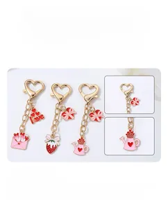 Détail des breloques enveloppe coeur rose et fraise sur un porte-clés doré avec motif love