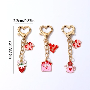Three gold heart keychains with pink and red enamel charms and heart lobster clasps