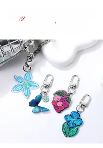 Close-up of colorful acrylic keychains with blue flowers and butterflies on a white bag