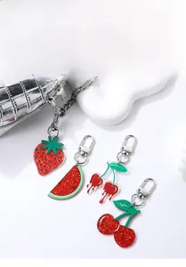 Détail de breloques de fruits en acrylique avec fraise et pastèque sur un sac argenté