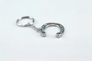 Close-up of silver horseshoe keychain with 888 lucky number engraving on metal surface