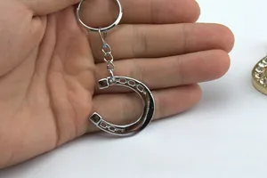 Macro shot of polished silver horseshoe keychain held in hand, showing metal texture