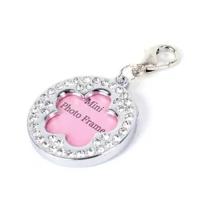 Detail of a round silver pet ID tag with sparkling rhinestones and pink floral center