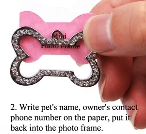 Detail of hand-held small bone-shaped pet ID tag with rhinestones and photo slot