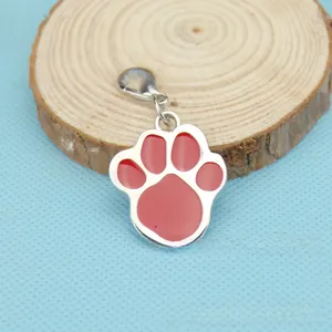 Detailed view of red dog paw pendant with silver trim on a wooden slice background