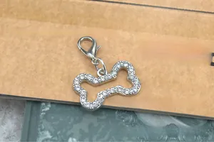Close-up of a silver bone-shaped pet tag with sparkling rhinestones and a lobster clasp