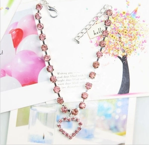 Close-up of pink rhinestone pet collar with a hollow heart pendant and adjustable silver chain