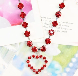 Close-up of a silver pet necklace with red gemstones and a hollow heart-shaped pendant
