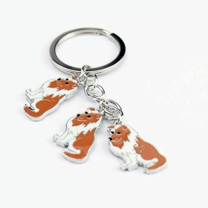 Detailed macro view of orange and white enamel dog charms on a metal keychain ring