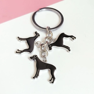 Detailed macro view of three black enamel dog charms on a silver metal keychain ring