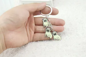 Detail view of pug themed metal keychain with colorful enamel pendants on a ring