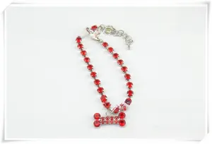 Detail view of the red rhinestone dog collar with a bone-shaped pendant and lobster clasp