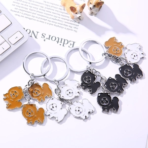 Creative enamel chow chow dog keychains in brown, white and black colors on white desk