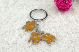 Detail of three brown poodle dog charms on a silver metal keychain over white plush