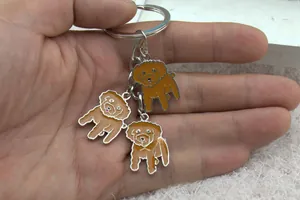Detail of metal keychain featuring brown enamel teddy dog charms and polished silver ring