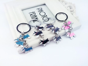 Close-up of four Scottie dog enamel keychains in blue, black, grey and pink on a frame