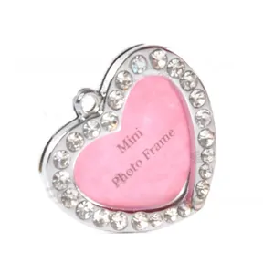Macro shot of silver heart-shaped photo frame charm with pink inlay and clear rhinestones