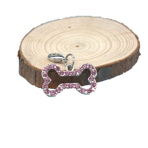 Silver bone dog tag pendant with pink rhinestones and lobster clasp on wood