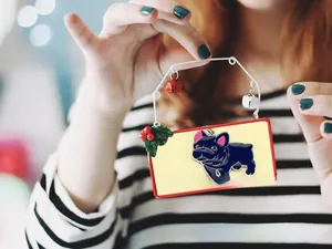 Close-up of black French bulldog keychain with bells and festive holly decorations