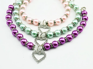 Detailed view of colorful faux pearl pet collars with rhinestone heart pendants in three colors