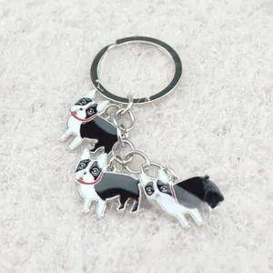 Close-up of three black and white enamel cartoon dog charms on a metal keychain