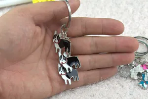 Detail of three black and white Boston Terrier enamel charms on a silver metal keychain