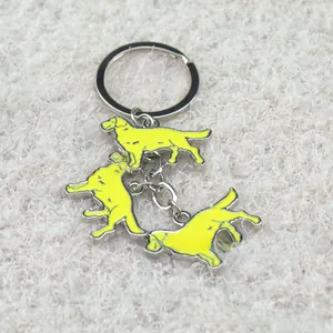 Detailed macro view of triple yellow enamel golden retriever charms on silver keychain