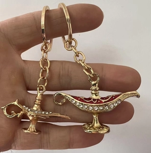 Detailed close-up of Aladdin magic lamp keychains with crystal inlay held by hand