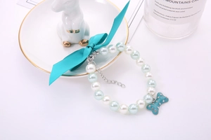Detail of mint green pet pearl necklace with ribbon bow and rhinestone bone pendant