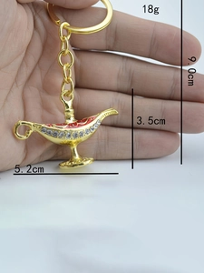 Macro shot of gold-plated Aladdin lamp keychain showing dimensions and rhinestone details