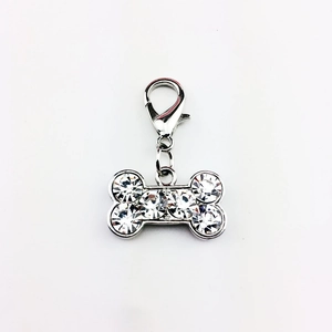 Dettaglio di un ciondolo per animali a forma di osso argento con strass e moschettone