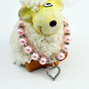 Close-up of pink faux pearl pet collar with a heart-shaped rhinestone pendant on a white background