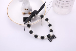 Detail of pearl pet collar with black ribbon bow and rhinestone bone pendant