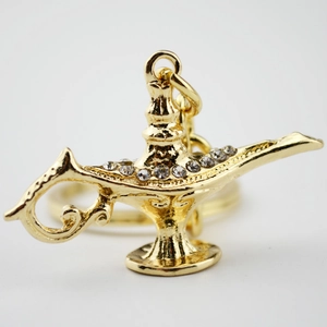 Macro detail of metal Aladdin lamp keychain with gold plating and white rhinestones