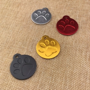 Detail of round aluminum pet ID tags with paw print design in four metallic colors
