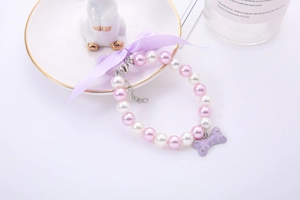 Macro detail of pearl pet necklace featuring a purple bone charm and satin bow