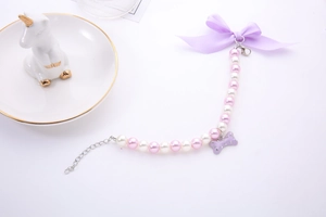Detail of pink pearl pet necklace with purple silk bow and sparkling bone pendant