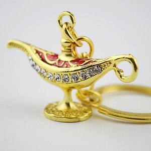Detail of golden Aladdin lamp keychain with red enamel and sparkling rhinestones