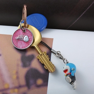 Detail of round fishbone pet tag with blue cartoon cat charm and golden key on a loop