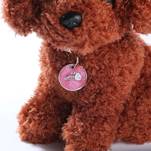 Detail of round pink glitter pet ID tag with fishbone pattern on a toy dog