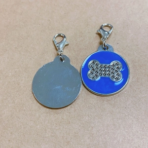 Detailed view of round pet ID tag with blue enamel and rhinestone bone pattern
