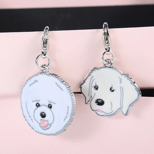 Close-up of white enamel dog pendants for keychains featuring Golden Retriever and Bichon