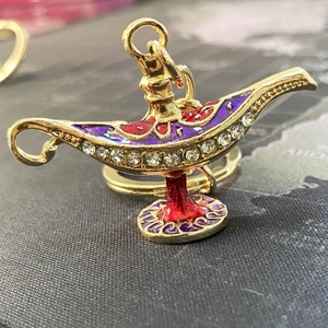 Detailed close-up of golden Aladdin lamp keychain with red enamel and sparkling rhinestones